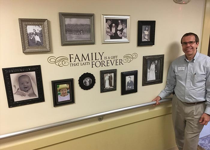 administrator joe bohunicky stands near the new photo wall at mount carmel rehabilitation and nursing center